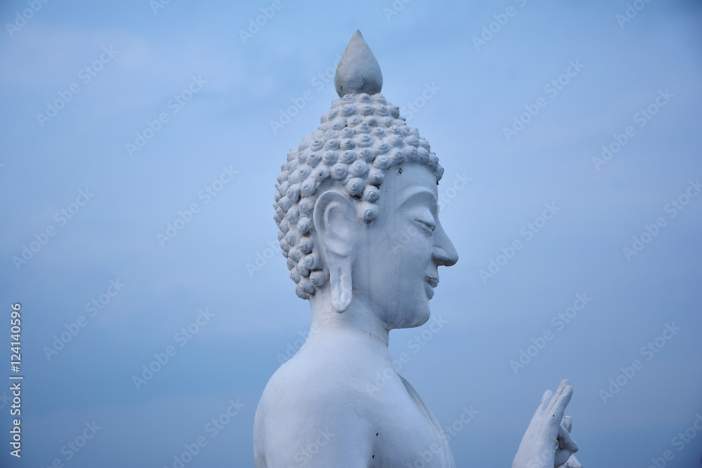 White Stone statue of a buddha on sky background in Thailand.