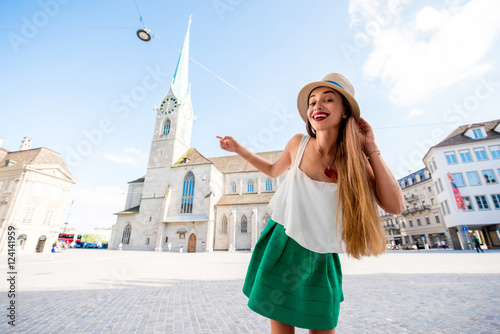 A portrait of a young female tourist in front of the famous church in the center of Zurich city. Having happy vacations in Switzerland