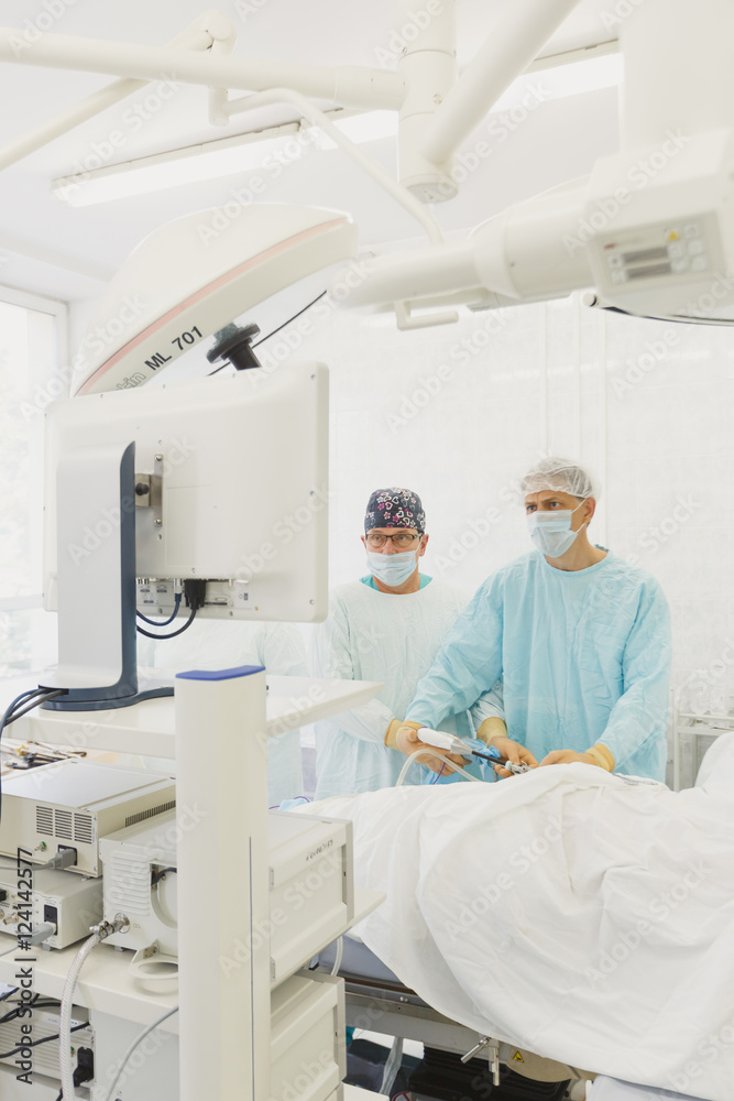 Surgeons team preforming operation in hospital operating theater, Surgeon operating patient,wearing surgical gown,operating room, holding hands,working with surgical instruments. Laparoscopy
