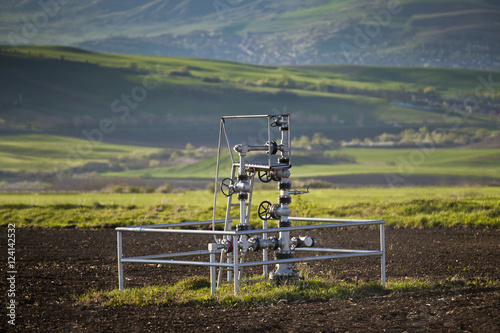 Natural gas wellhead in a meadow of green grassland field