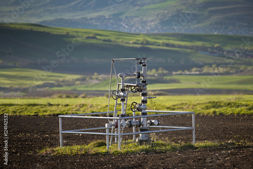 Natural gas wellhead in a meadow of green grassland field photo