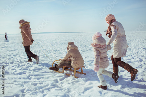 Happy big family walk on a field in winter sunny day (back view)