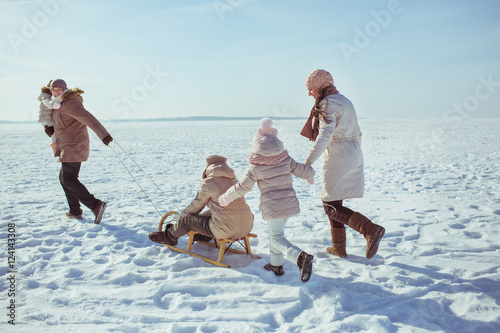 Happy big family walk on a field in winter (back view)