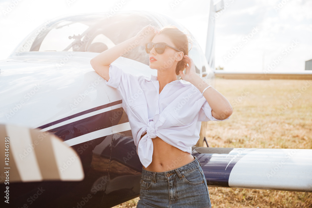 Obraz premium Woman in sunglasses standing outdoors near small plane