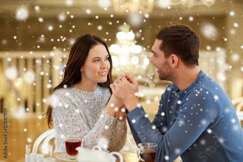 happy couple with tea holding hands at restaurant