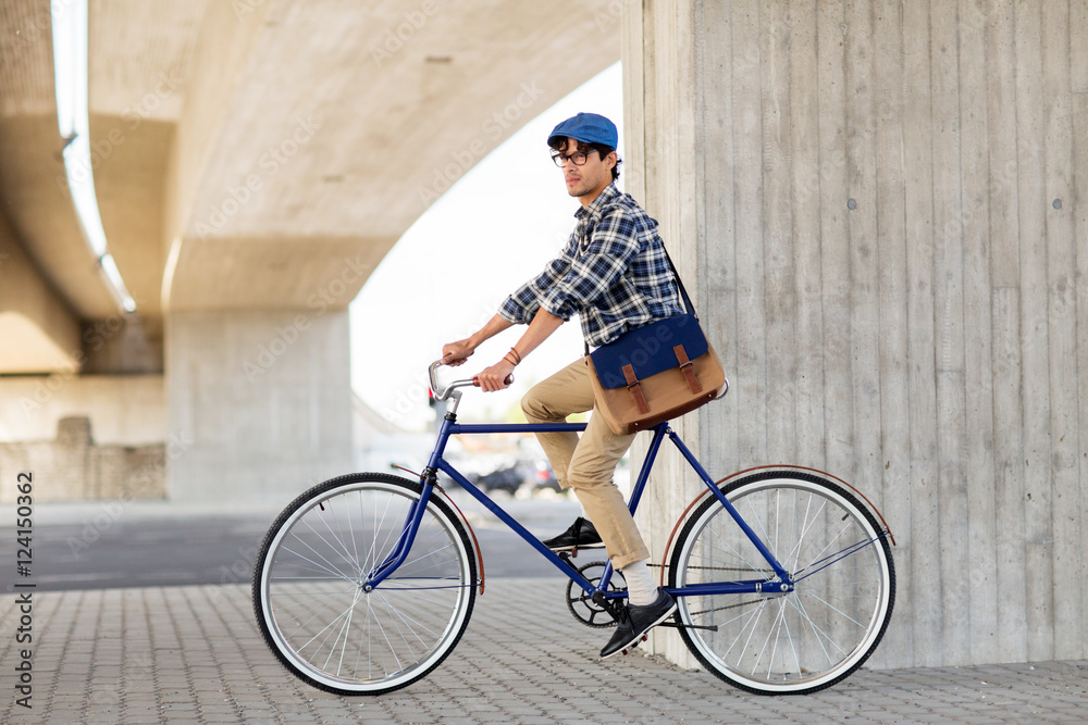 Naklejka premium young hipster man with bag riding fixed gear bike