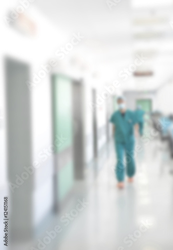 Doctors and nurses walking in hospital hallway, blurred motion.
