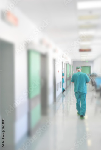 Doctors and nurses walking in hospital hallway, blurred motion.
