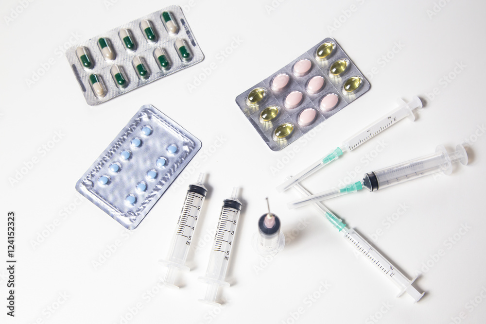 Medicine pills or capsules with syringe on white background. Drug prescription for treatment medication. Pharmaceutical medicament. Injection with vaccine Medicine pills or capsules with syringe on white background. Drug prescription for treatment medication. Pharmaceutical medicament. Injection with vaccine