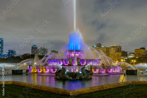 Chicago skyline panorama with skyscrapers and Buckingham fountain in Grant Park at night lit by colorful lights.