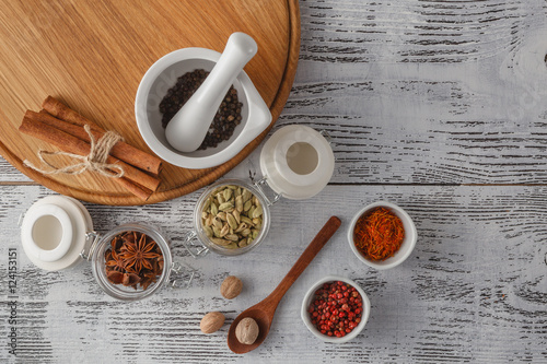 Foto Mortar and pestle with pepper and spices on wooden table