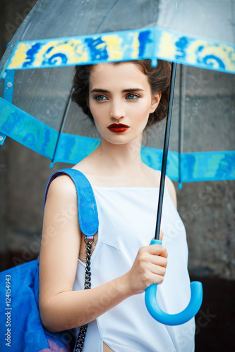Fashionable young woman with retro hair, umbrella posing at street