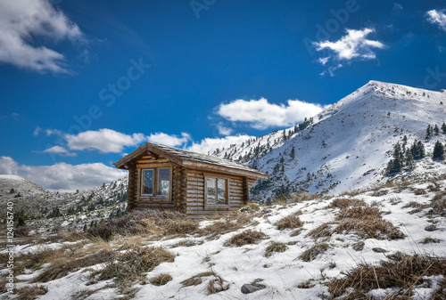 Winter snowy landscape with cabin hut amd blue sky and clouds on mountain Helmos near Kalavryta town in Greece photo