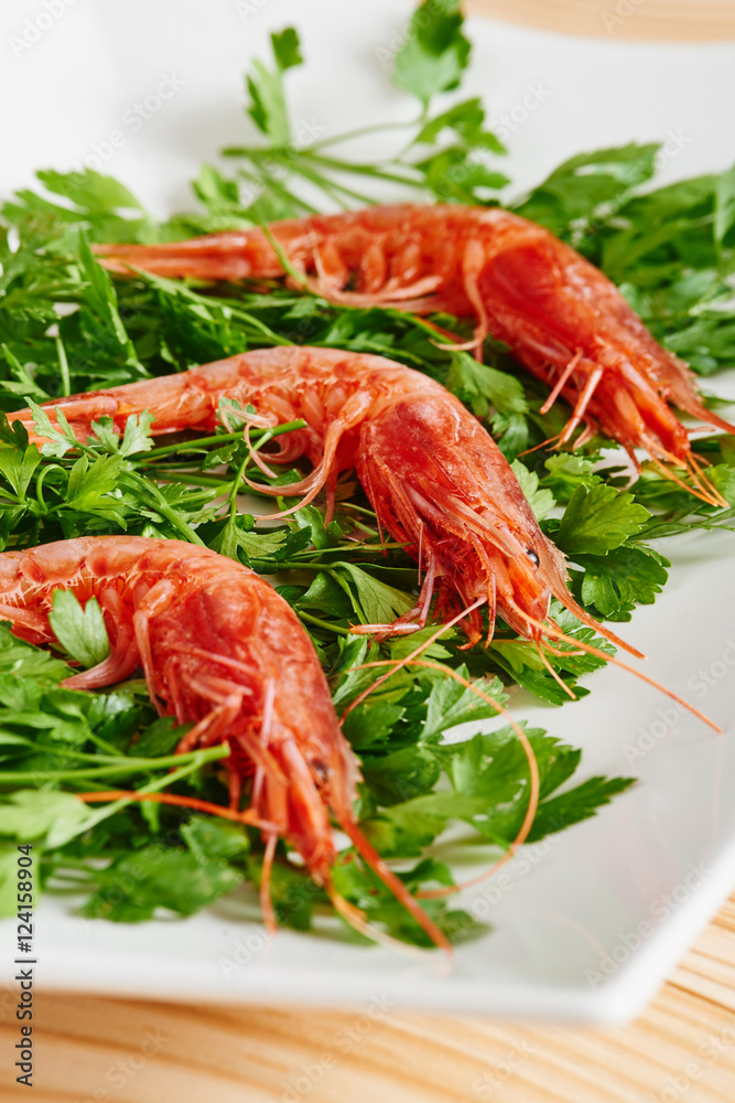 Raw prawns and parsley on white dish Raw prawns and parsley on white dish