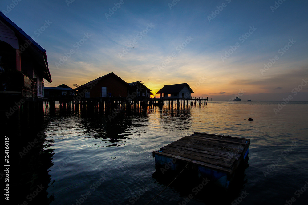 silhouette wooden village on sea sunset sky