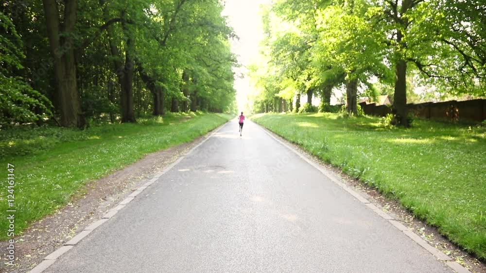 Mixed race African American young adult teenager girl running jogging on a tree lined country road Mixed race African American young adult teenager girl running jogging on a tree lined country road