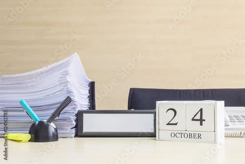 Closeup white wooden calendar with black 24 october word on blurred brown wood desk and wood wall textured background in office room view with copy space , selective focus at the calendar