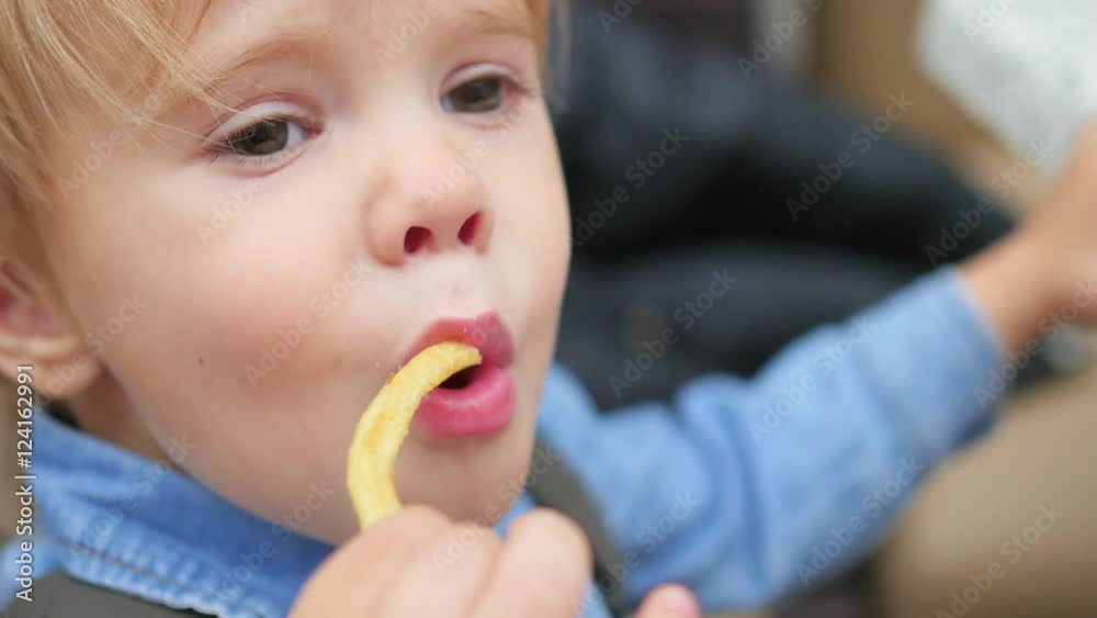 the kid eats a fried potato at a fast food restaurant closeup the kid eats a fried potato at a fast food restaurant closeup
