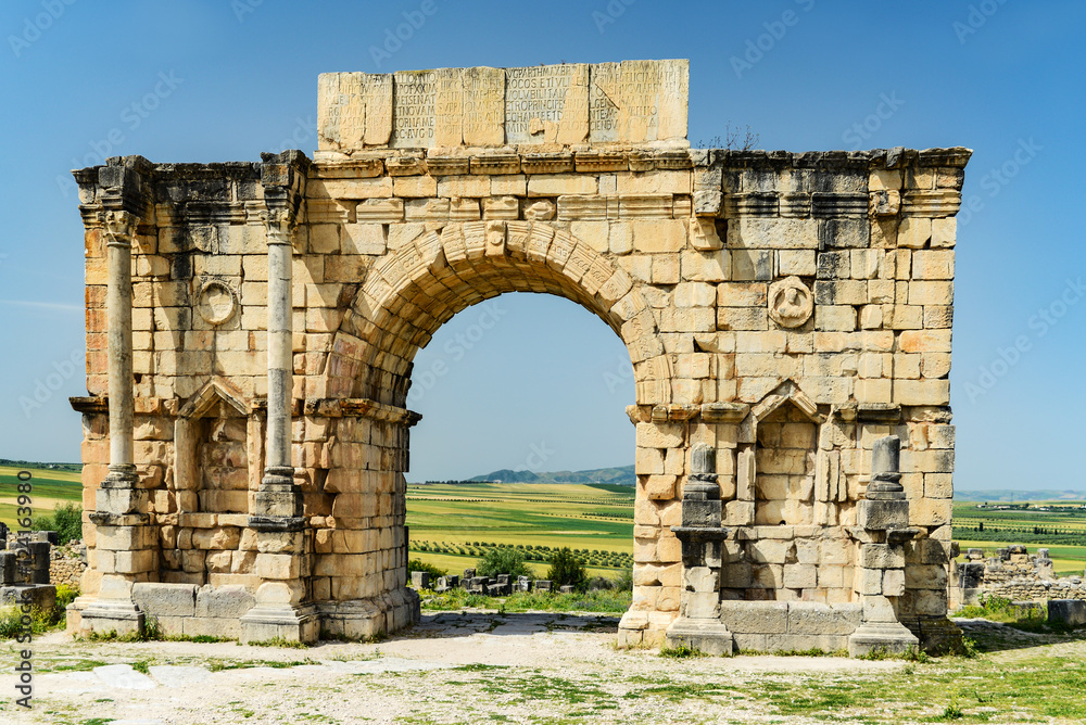 triumphal arch with latin inscription in ancient ruins of roman volubilis
