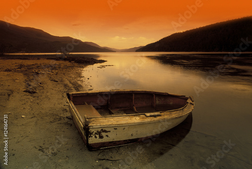 Row Boat At Water's Edge Against Sunset Backdrop