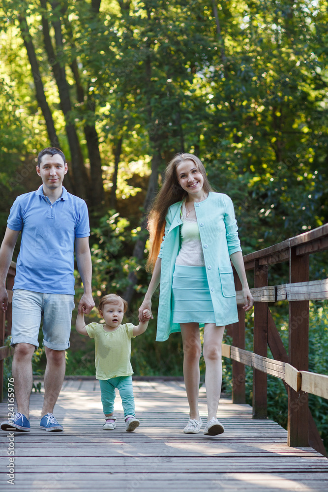 Family holding hands with petite daughter in summer park Family holding hands with petite daughter in summer park