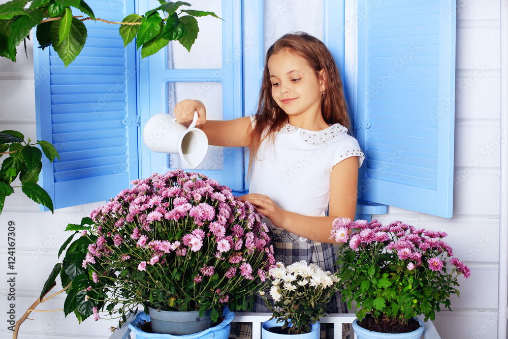 beautiful curly little girl watering flowers. 
