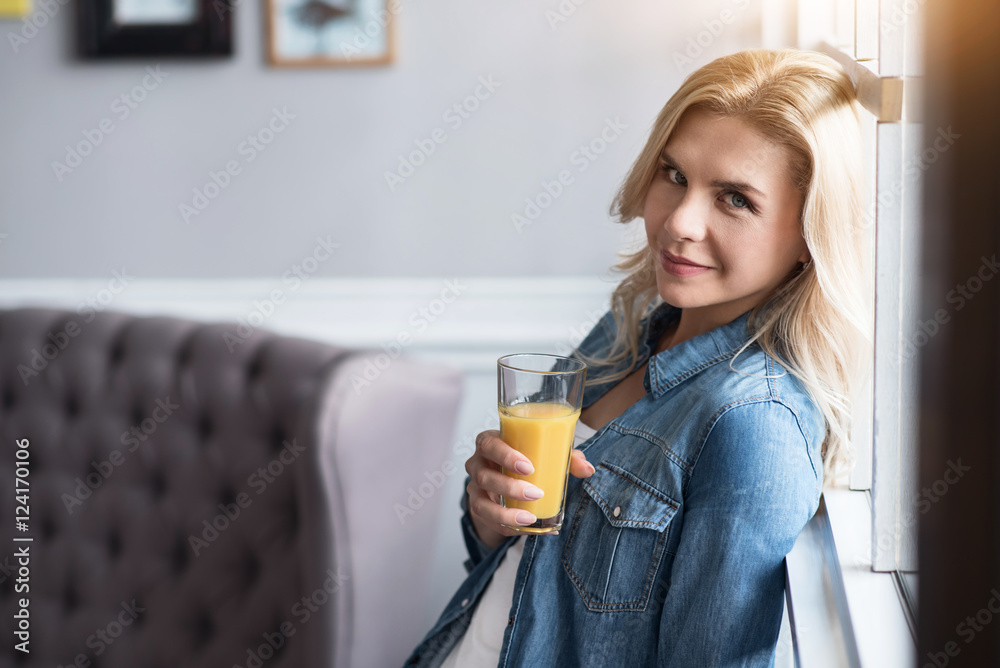 Pretty blond woman with juice at window Pretty blond woman with juice at window