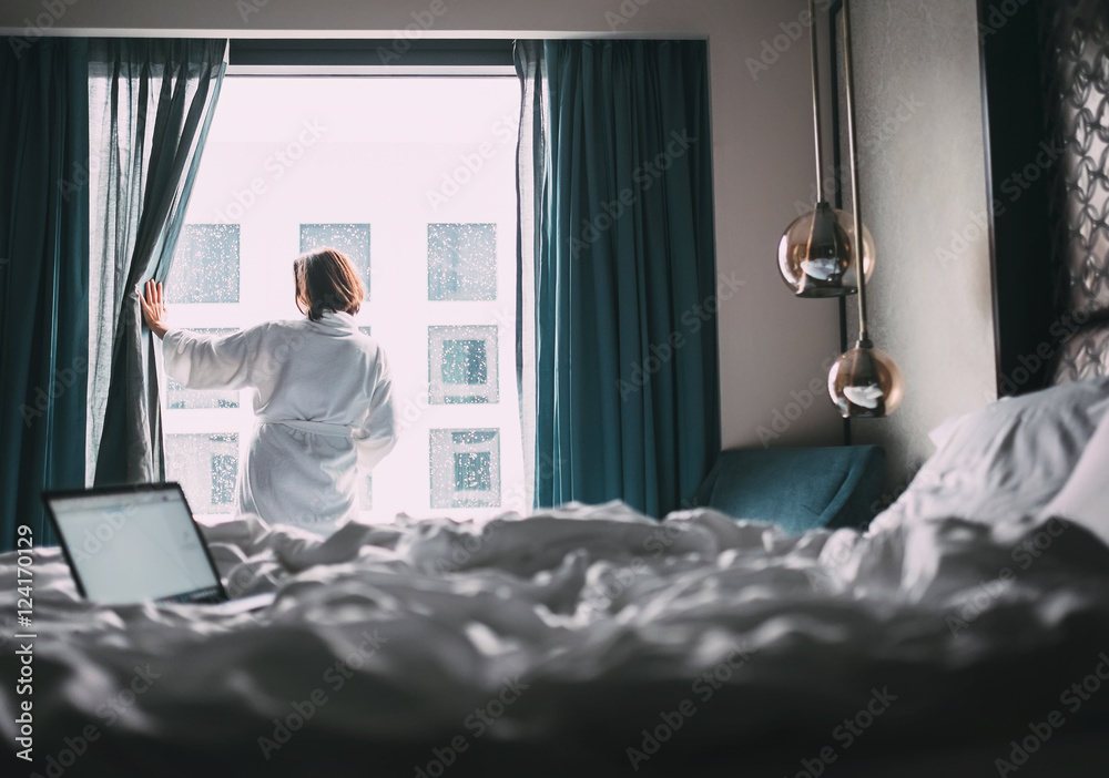 Woman in white robe stay hear the window in hotel room - obrazy, fototapety, plakaty 