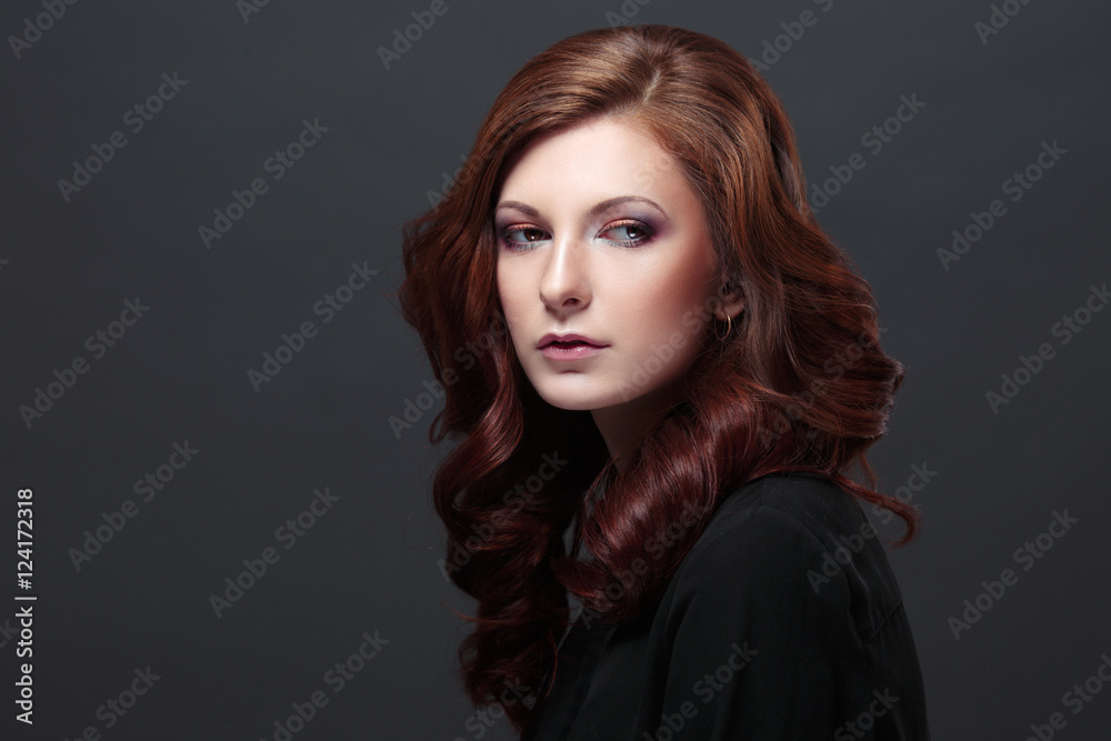 Beautiful model with long curly hair,  fashion makeup and Hairstyle curls, isolated on a black background.