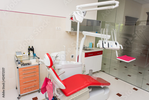 Dentistry. Dental office with modern dental units, chairs, equipment, tools used by dentists. Cabinet in red and white colors
