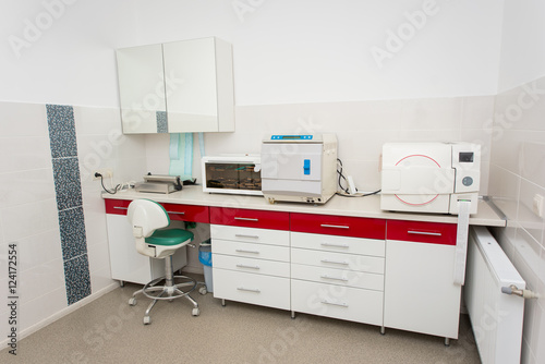 Modern sterilization room for the handling of dental instruments. Table with a packaging machine, ultraviolet shelf, sterilizer, autoclaving © anatoliy_gleb