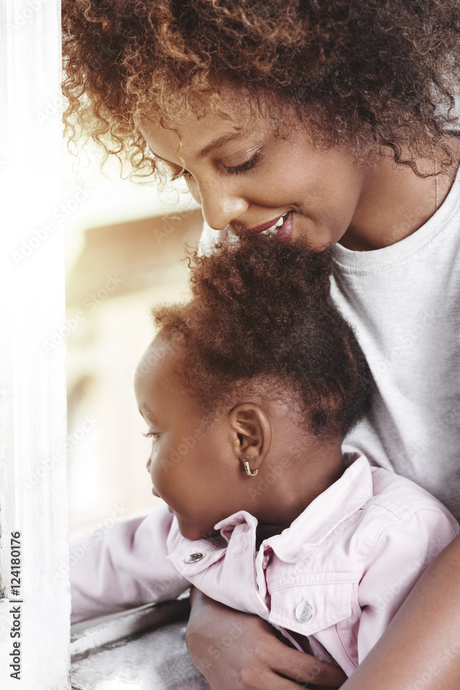Fototapeta premium Mother holding baby at the window and smiling