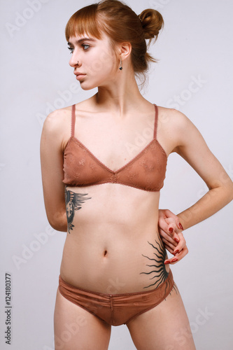 Girl in lingerie with tattoo lying on his stomach on a white background © alexbutko_com