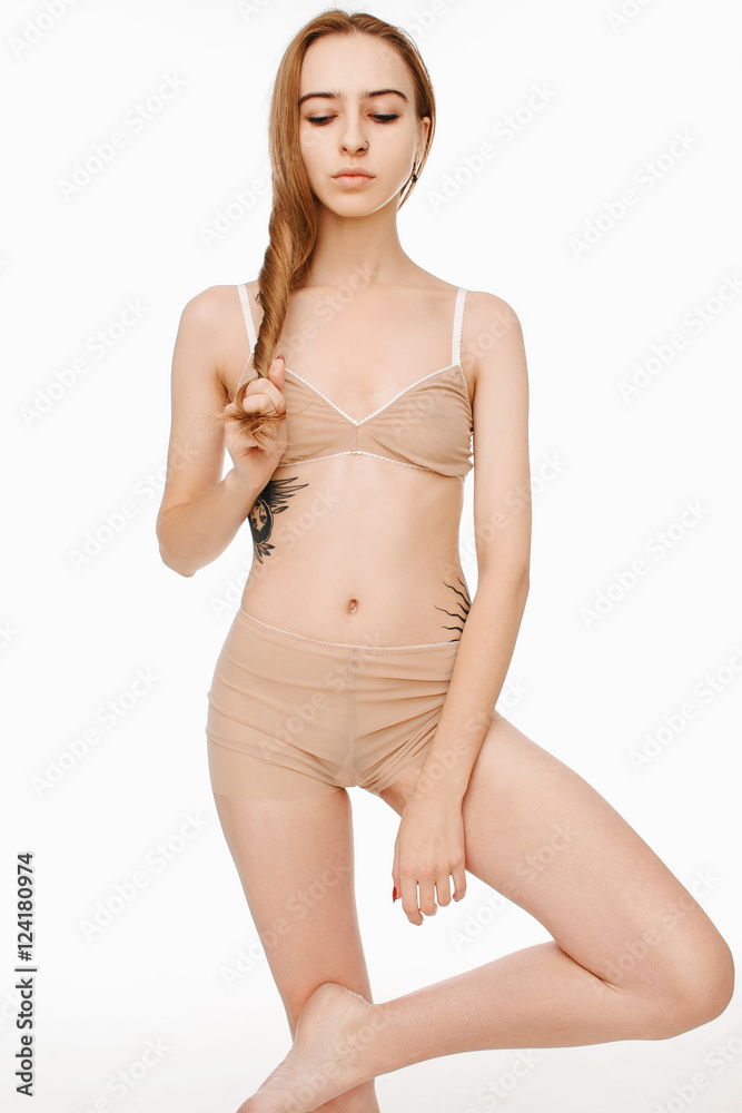 Fototapeta premium Girl in lingerie with tattoo lying on his stomach on a white background