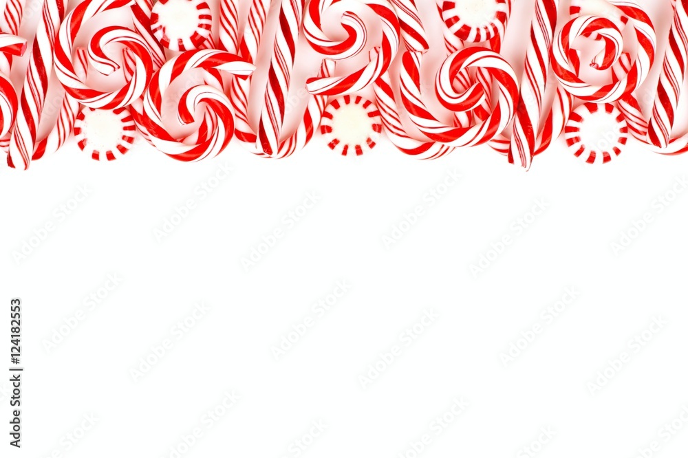 Christmas candy top border with peppermints and candy canes over a white background Christmas candy top border with peppermints and candy canes over a white background
