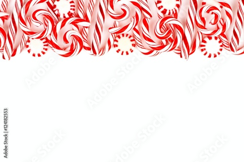 Christmas candy top border with peppermints and candy canes over a white background