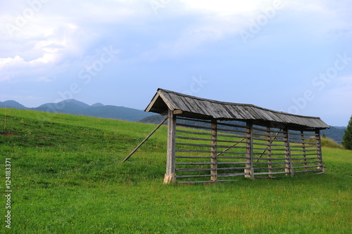 Traditional retro vintage wooden hayrack on the lush green Alpine meadow, Slovenia, Europe