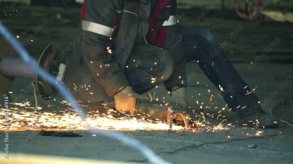 Construction worker cuts metal with a angle grinder on a construction site, slow motion