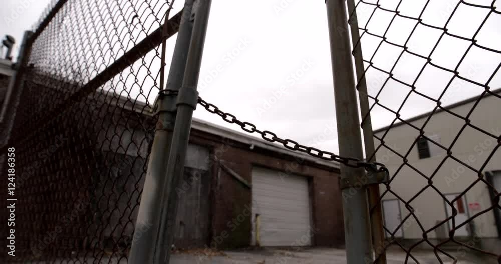 Locked metal gate behind industrial building Locked metal gate behind industrial building