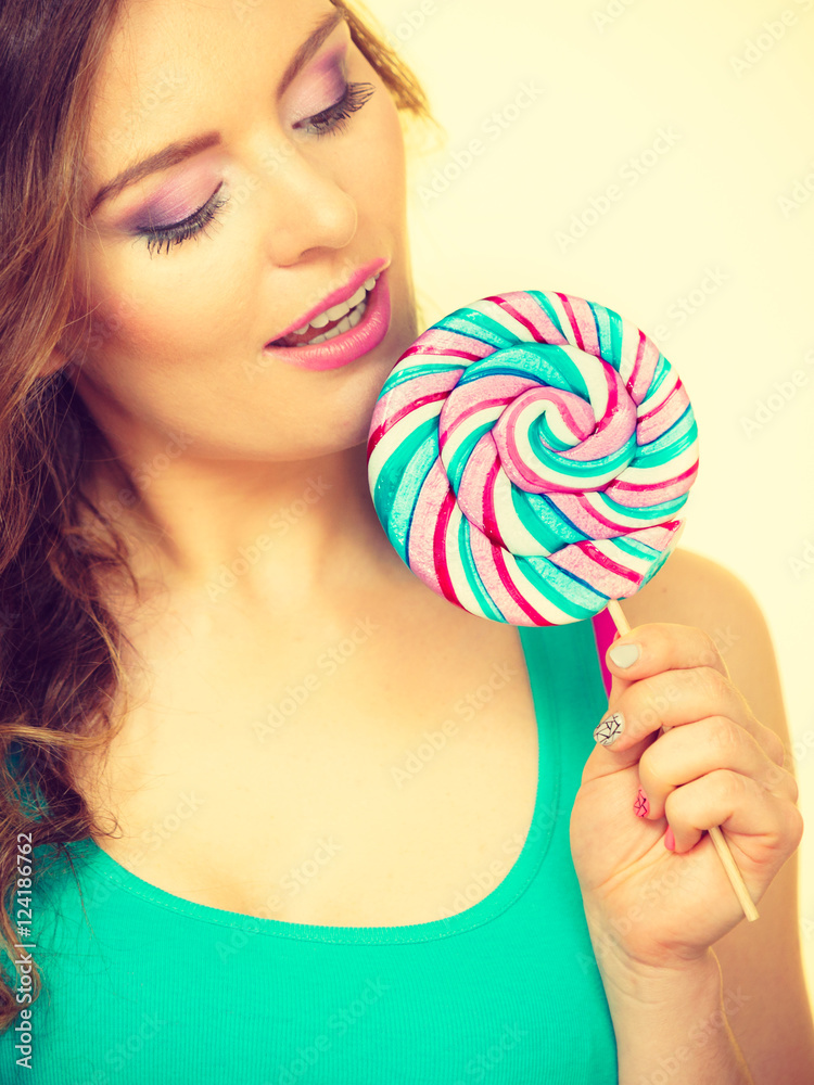 Woman charming girl with lollipop candy