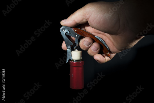 hand man using corkscrew to open a bottle of wine