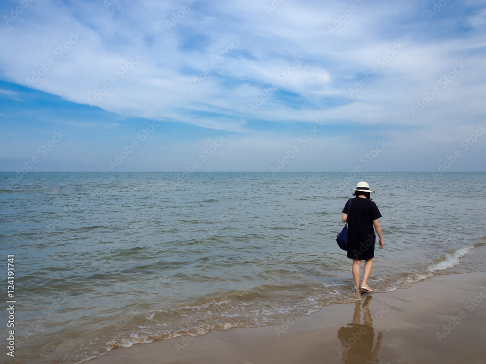 Woman in black dress walking along the beach