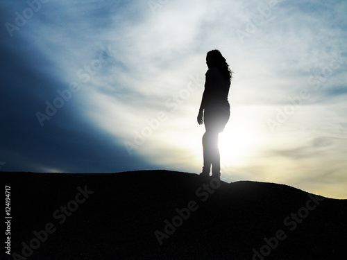 Silhouette of woman standing on a hill with dramatic effected sk