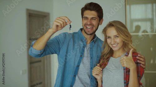 Happy couple holding a key of new apartment.
