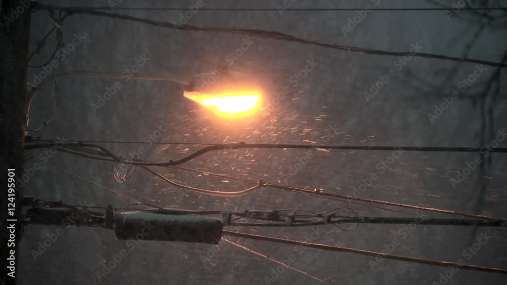Close up of lamppost and power lines during snowfall
