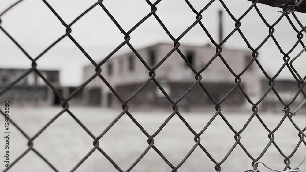 Close up of chain link fence against abandoned warehouse Close up of chain link fence against abandoned warehouse