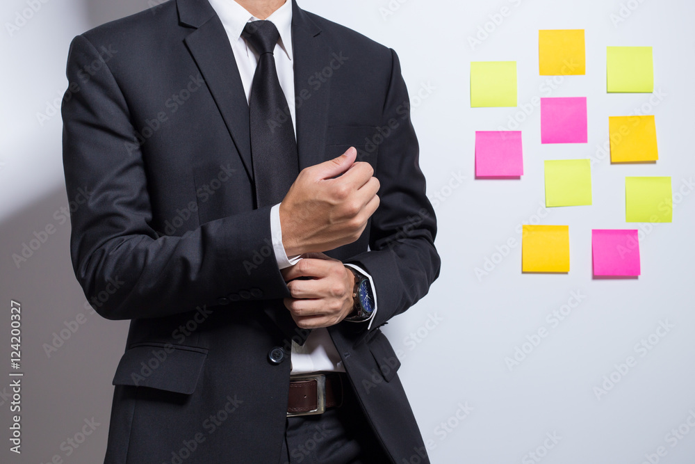 Businessman adjusting his costume on notepaper background Businessman adjusting his costume on notepaper background
