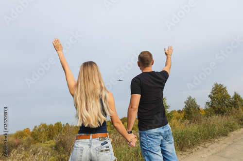 Newlywed couple planning the trip for the honeymoon. Monuments and plane background backlit on sunset sky. plane takes off into the sky