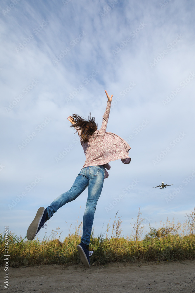Young beautiful girl jumping happy journey. It looks like a plane taking off from the runway. Young beautiful girl jumping happy journey. It looks like a plane taking off from the runway.