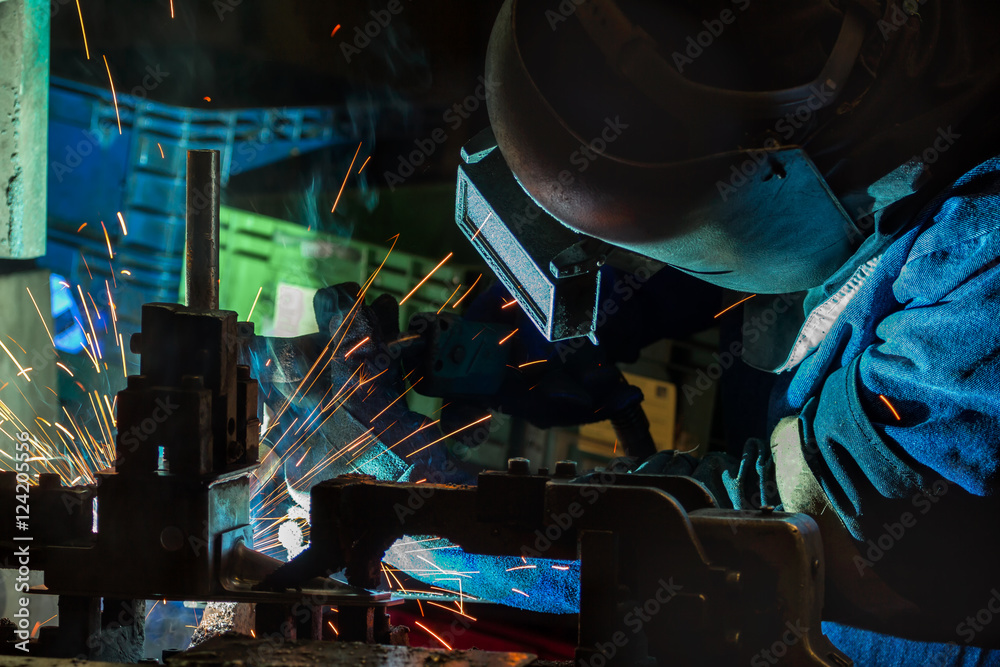 Industrial Worker at the car factory is welding assembly automotive part, closeup Industrial Worker at the car factory is welding assembly automotive part, closeup